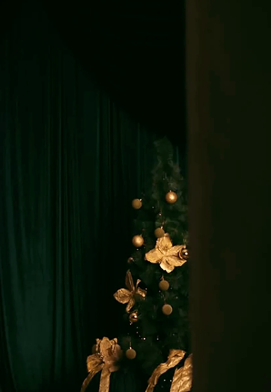 Árvore de Natal parcialmente revelada atrás de cortinas verde-escuras