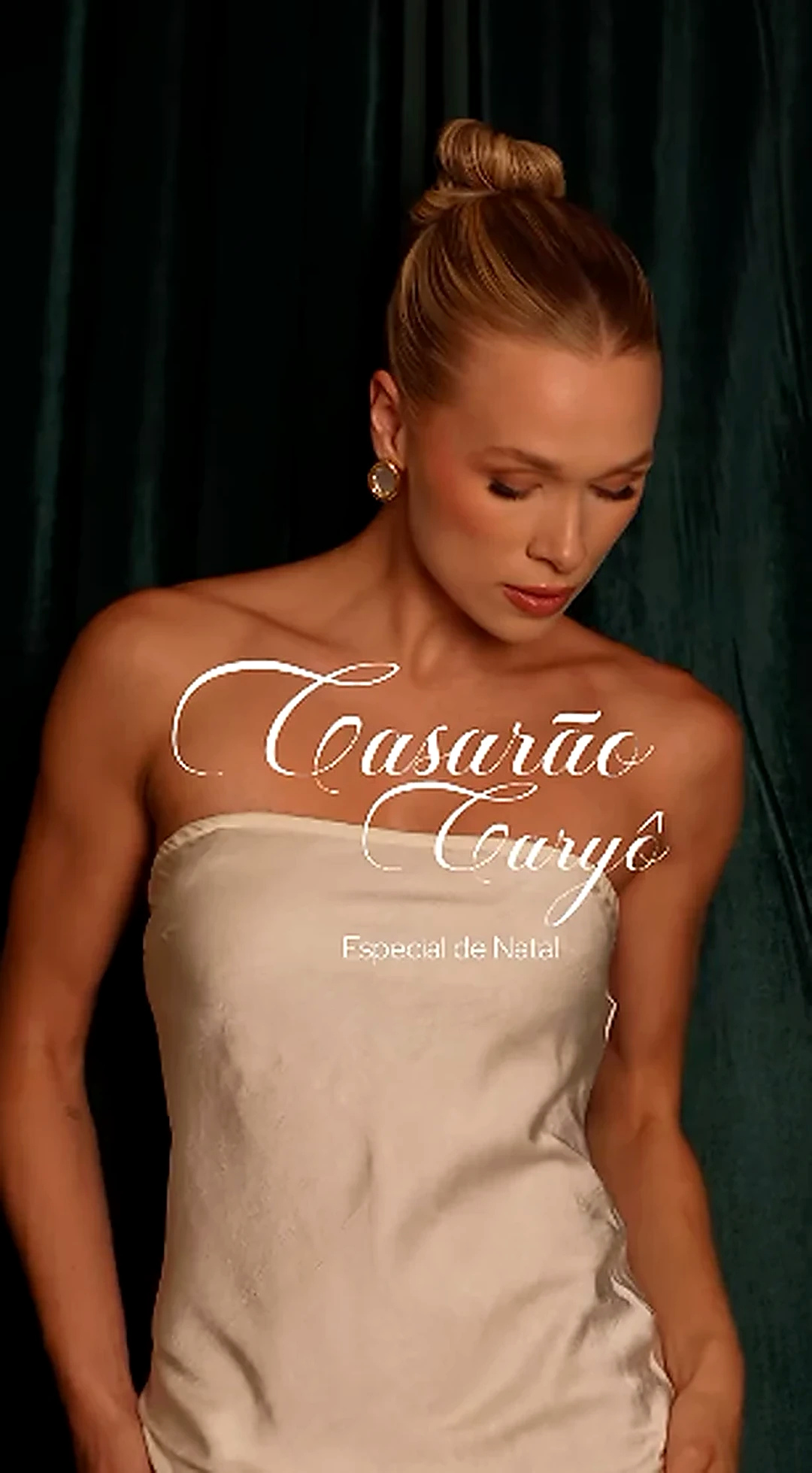 Retrato editorial da modelo de vestido claro diante de cortina verde-escura, com identidade do Especial de Natal